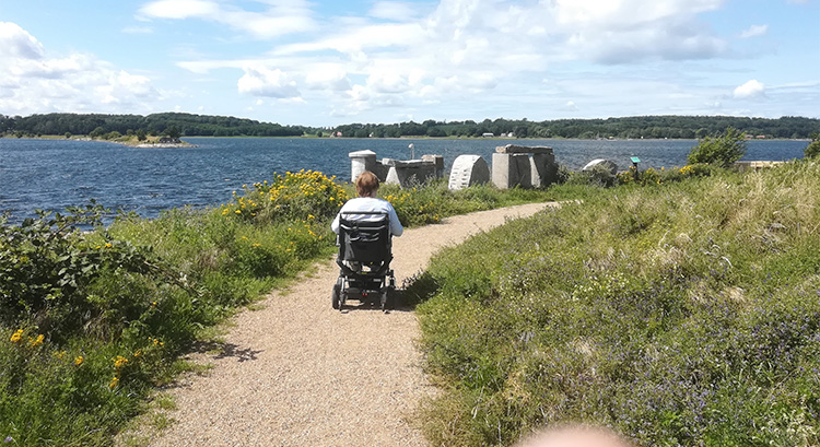 Merete og Kompas på grussti med udsigt over sø. Privat foto