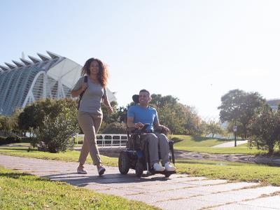 Aviva RX40 lifestyle foto. Ung par ude i solen. Mand i blå el-kørestol, elektrisk kørestol fra Invacare