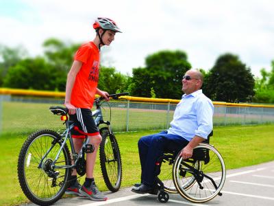 Matrx Elite E2 lifestyle foto - Mandlig kørestolsbruger i kørstol med Matrx ryg + dreng med cykel